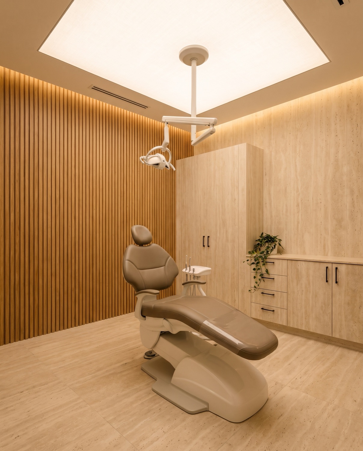 A private treatment room with a new dental chair and oak-slat wall
